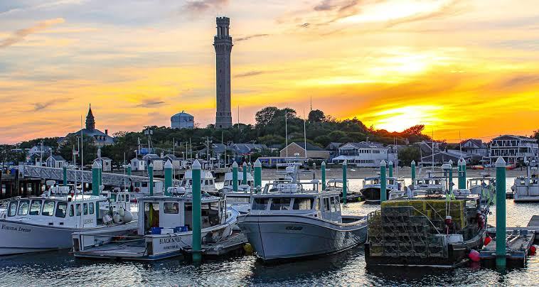 Provincetown harbor at sunset, fishing boats and lobster traps below the Pilgrim Monument